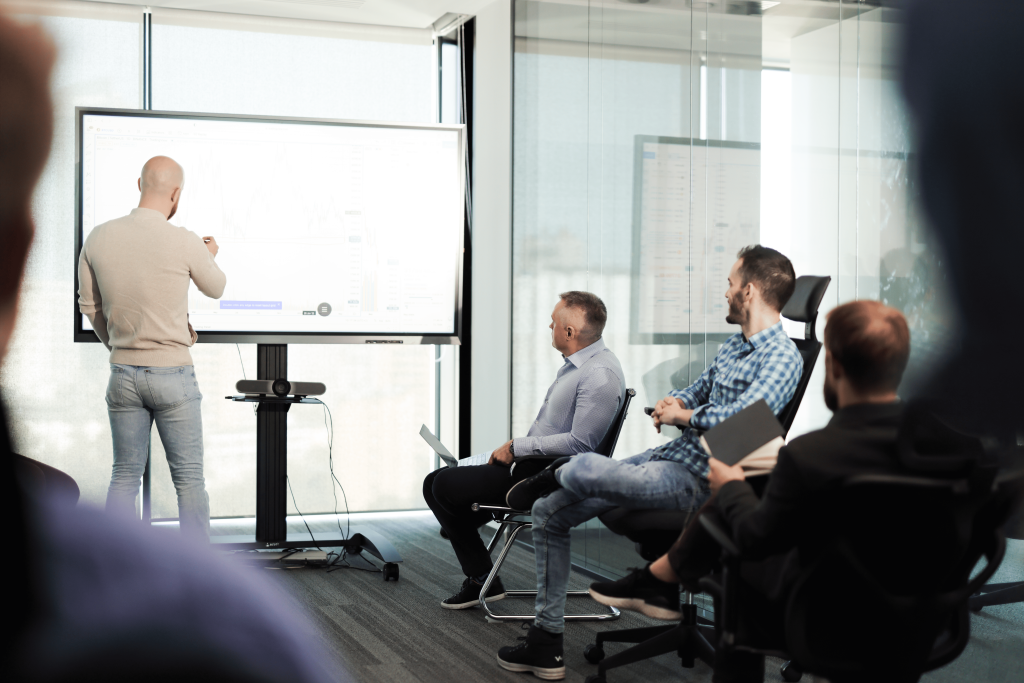 Man pointing to data on the screen during a team meeting at the WOO office.